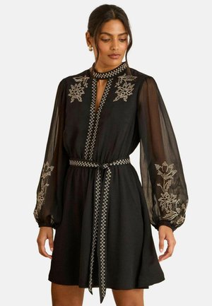 Schwarzes Kleid mit transparenten, gepufften Ärmeln und bestickten Blumenmustern. Verfügt über einen Ausschnitt mit Schlitz und einen passenden Gürtel mit dekorativem Besatz.