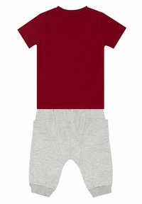 T-shirt rossa in cotone con maniche corte abbinata a pantaloni jogger grigi in cotone con tasche e polsini a coste. Design pulito, vestibilità confortevole.