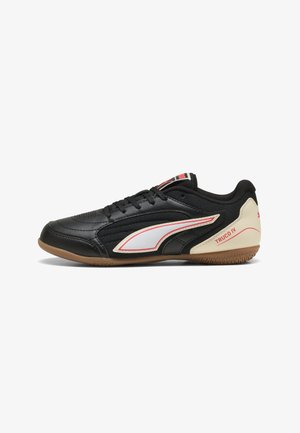 Schwarzer Puma Truco IV Hallenfußballschuh mit weißen und beigen Akzenten und Gummisohle, von der rechten Seite dargestellt.