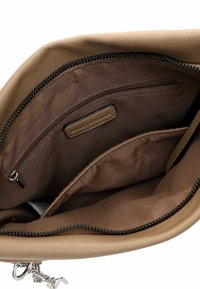 Beige leather handbag interior with a soft brown fabric lining. Features a zip pocket and a label tag, emphasizing organized storage.