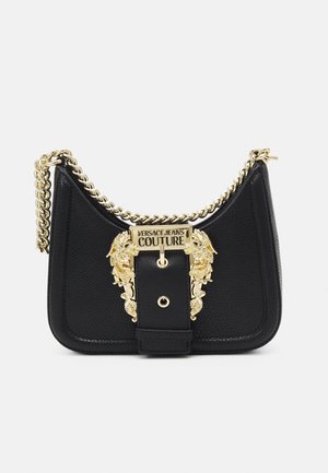 Czarna skórzana torebka na ramię z złotym łańcuszkiem oraz ozdobną złotą klamrą z wygrawerowanym napisem "Versace Jeans Couture" umieszczonym centralnie z przodu.