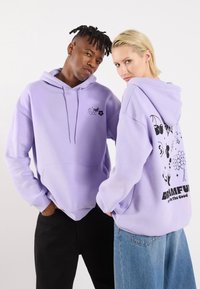 Lilla hettegensere med frontlomme og hette med snøring. Forsiden har et lite grafisk motiv; baksiden viser et større grafisk motiv med ulike design.
