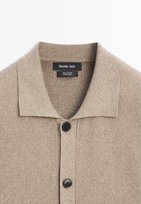 Cardigan in maglia beige a coste con bottoni neri e collo risvoltato, etichettato Massimo Dutti, 100% cotone, prodotto in Cina.
