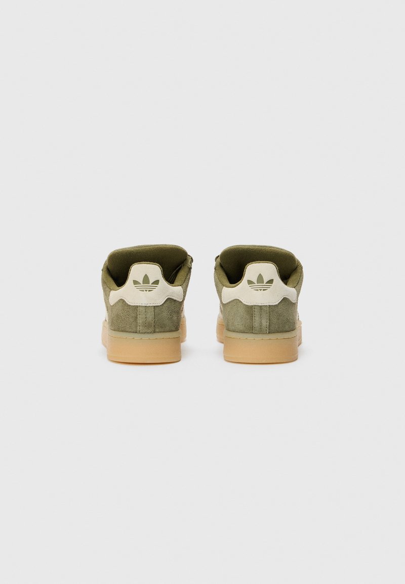 Sneaker in suede verde con suola in gomma beige, caratterizzate da un logo bianco sul tallone e un collare imbottito per il massimo comfort. Design minimalista nel complesso.