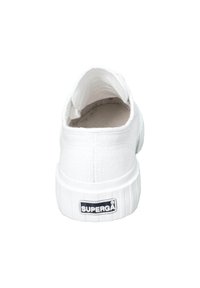 Sneaker bianca in tela con superficie testurizzata, tacco arrotondato e suola in gomma rigata. Presenta un etichetta nera con "SUPERGA" sul retro.