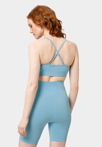 Světle modrá žebrovaná sportovní podprsenka a šortky s vysokým pasem. Design s římskými popruhy a křížovými popruhy. Hladká textura s přiléhavým střihem.