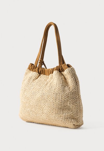 Sac cabas tissé beige avec motif texturé, bord supérieur froncé marron et doubles bretelles, posé sur un fond blanc.