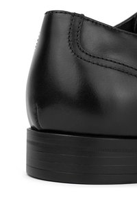 Czarna skórzana puma o gładkim wykończeniu, z zaokrąglonym obcasem i teksturowaną czarną podeszwą. Subtelne detale przeszycia przy górnej krawędzi.