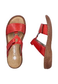 Sandales en cuir rouge avec un design de bride texturée, dotées d'un accent métallique circulaire. Semelle en caoutchouc marron avec des détails de couture et une semelle intérieure rembourrée.