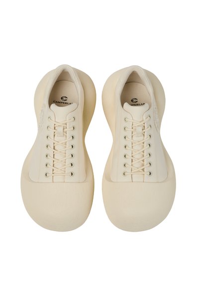 Paire de baskets beige oversize avec bouts arrondis et lacets sur le devant, vues de dessus sur fond blanc.