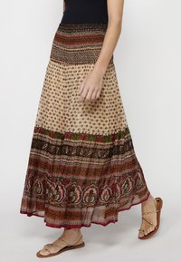 Maxi skirt featuring a tiered design with vibrant red and green patterns, a smocked waistband, and lightweight, flowing fabric.
