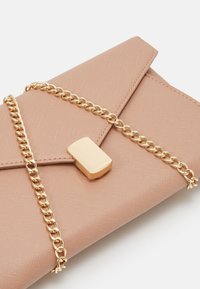 Růžová obálková kabelka vyrobená z texturovaného materiálu, s zlatým řetízkem a obdélníkovým zlatým uzávěrem.