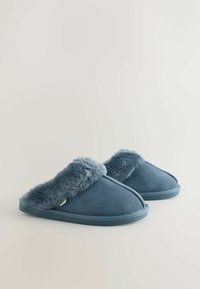 Blauwe suède pantoffels met een zachte nepbont voering. Het ontwerp heeft een open achterkant en gestikte accenten langs de randen.