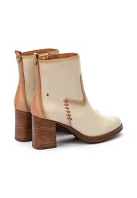 Beige leather ankle boots with brown accents, stacked wooden heels, and decorative stitching. Zippered back for easy wear.