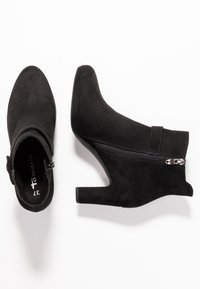Zwarte suède enkellaarsjes met een puntige neus en een ritssluiting aan de zijkant. Heeft een slanke, hoge hak en gestikte accenten voor extra detail.