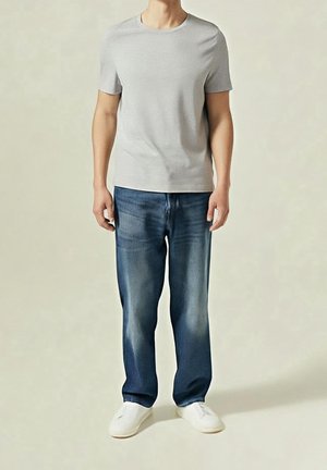 Harmaa puuvillainen pyöreäkaulainen t-paita, yhdistettynä sinisiin haalistettuihin suoraan lahkeeseen oleviin farkkuihin ja valkoisiin liukuvaiskengissä. Yksinkertainen, rento asu, jossa on selkeät linjat.