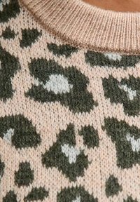 Brede gebreide trui met een luipaardprint in donkergroen en crème op een zachte roze achtergrond, met een geribbelde halslijn voor extra textuur.