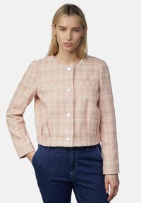 Roze tweed jasje met een ronde hals en lange mouwen, voorzien van zilveren knopen en een textuurstof, gecombineerd met donkere spijkerbroeken.