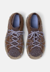 Brown outdoor sneakers with a textured knit upper, contrasting lavender laces, and a rugged, speckled outsole. Dual-tone design throughout.