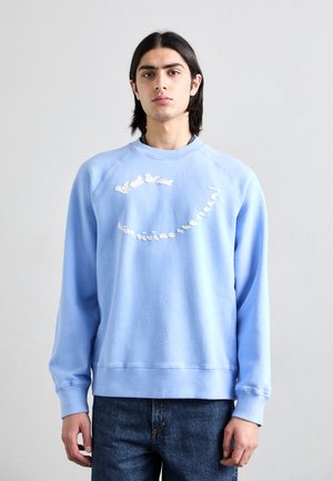 Blauer Pullover aus weichem Material, mit Rundhalsausschnitt und Raglanärmeln. Er ist mit weißem, gesticktem Text auf der Brust versehen.