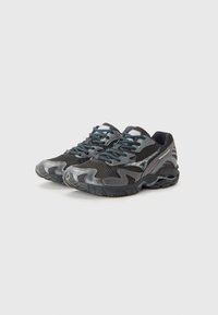 Sport sneakers in black and gray mesh with textured overlays, featuring dark laces and a thick rubber sole with a wavy design.