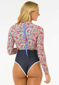 Maillot de bain à manches longues avec un motif floral multicolore, détails de fermeture éclair bleus, et un bas taille haute bleu marine avec des accents blancs.