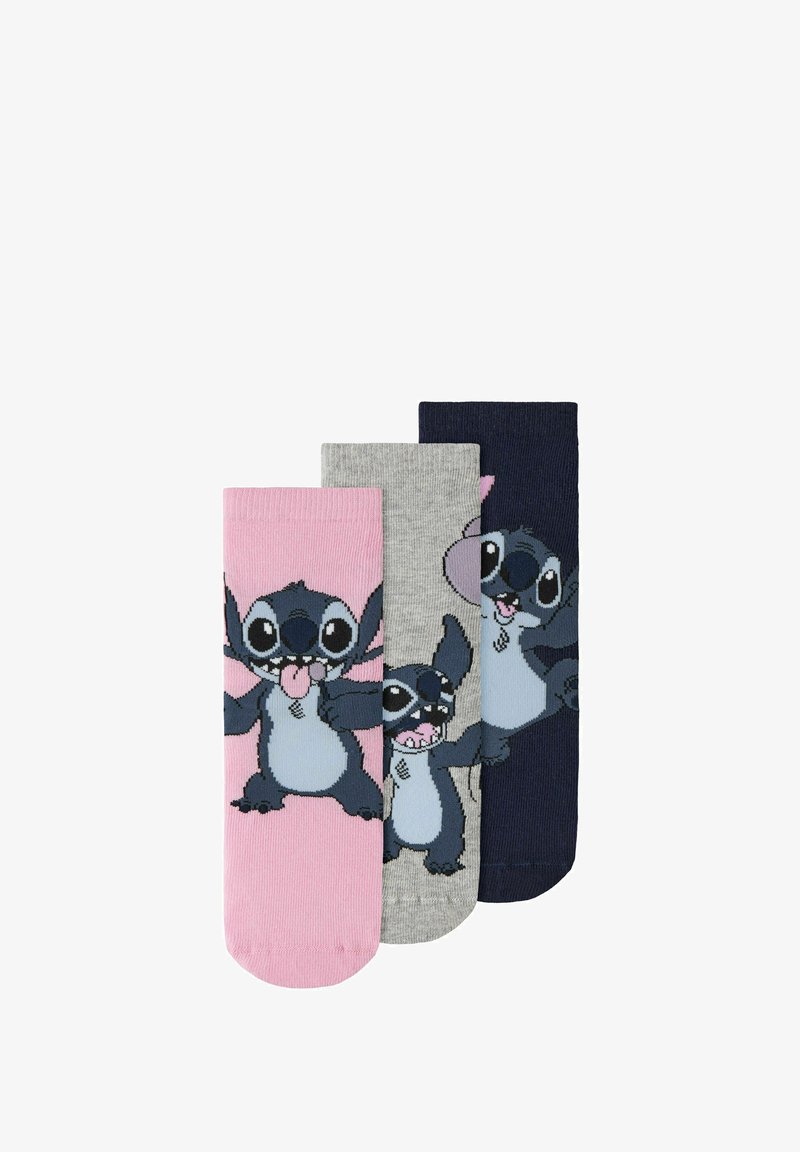 Trois paires de chaussettes rose, grise et bleu marine, chacune avec un personnage de dessin animé aux grands yeux et à l'expression espiègle.