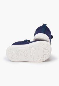 Zapatos de tela azul marino con tiras ajustables. La suela de goma blanca presenta un diseño texturizado de huellas de patas. Talla 21 indicada en la suela.