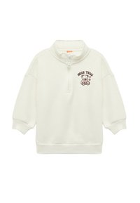 Valkoinen vetskarihousu, jossa on korkea kaulus, sisältää ruskean karhun grafiikan ja tekstin "BEAR TEAM". Pehmeä materiaali ja rento istuvuus.