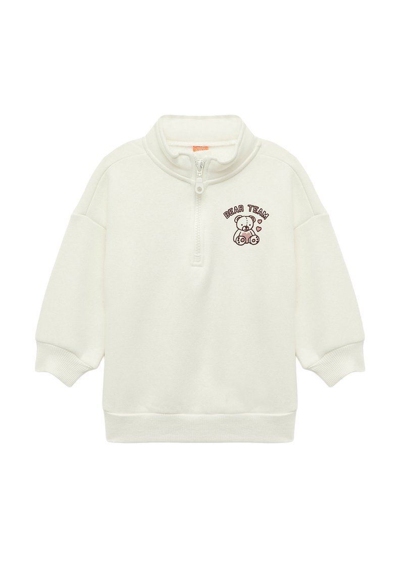 Valkoinen vetskarihousu, jossa on korkea kaulus, sisältää ruskean karhun grafiikan ja tekstin "BEAR TEAM". Pehmeä materiaali ja rento istuvuus.