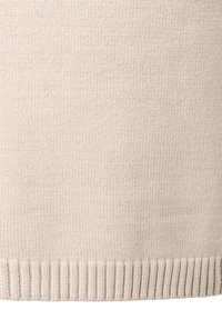 Beiger Strickpulloverstoff mit glatter Textur und geripptem Saum. Das Strickmuster ist durchgehend gleichmäßig und konstant im Material.