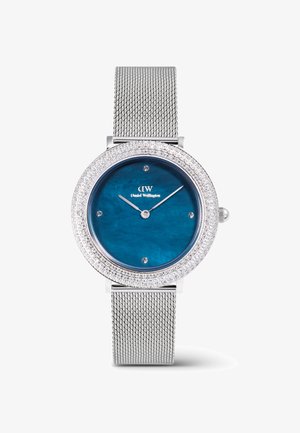 Sudraba sieta jostas pulkstenis ar apaļu zilu ciparnīcu, kristāliem izrotātu rāmīti un minimālisma sudraba stundas un minūtes rādītājiem.