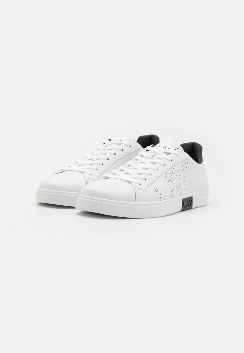 Weiße Sneakers aus Leder mit glatter Textur, die über durchbrochene Designelemente, flache Schnürsenkel und einen schwarzen Akzent an der Ferse verfügen.