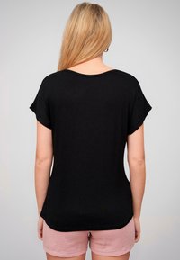 T-shirt noir à manches courtes avec un ourlet arrondi et une coupe décontractée, fabriqué à partir d'un tissu doux et léger. Avec un col large.