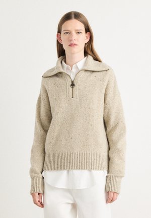Beige knitted sweater with a high collar, quarter-length zipper, and ribbed cuffs and hem. Features a speckled texture for added detail.