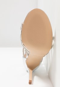 Silberne High-Heel-Sandale mit dünnen Riemen und Strassakzenten. Glatte Oberflächenstruktur und strukturierte Sohle, konischer Absatz und neutrale Innensohle.