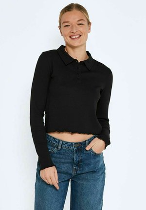 Black ribbed long-sleeve top with a collared neckline, button closure, and scalloped hem, paired with high-waisted blue denim jeans.