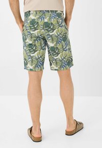 Shorts con un motivo di foglie tropicali verdi e bianche, realizzati in un tessuto leggero, con due tasche posteriori e una vestibilità dritta.