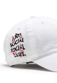 Biała bawełniana czapka bejsbolowa z czarnym haftowanym napisem "ANTI SOCIAL SOCIAL CLUB" oraz różowymi kwiatowymi akcentami. Regulowany pasek z tyłu.