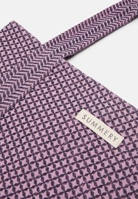 Fioletowa torba na ramię z geometrycznym wzorem, wykonana z teksturowanej tkaniny, z metką z napisem "SUMMERY" w białych literach.