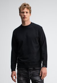 Schwarzer gestrickter Sweatshirt mit geripptem Kragen und Bündchen, ausgestattet mit einem klassischen Rundhalsausschnitt und einer weichen, strukturierten Oberfläche.