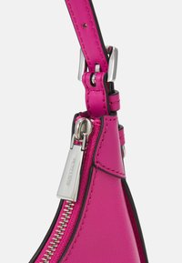 Manico di borsa in pelle rosa con hardware argentato, caratterizzato da un dettaglio con cerniera e rifiniture nere, che mette in risalto un design elegante e moderno.
