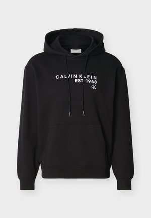 Sort hættetrøje med frontlomme, snore og hvid "CALVIN KLEIN EST 1968 cK" tekst trykt hen over brystet.