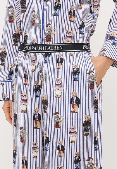 Conjunto de pijama às riscas com motivos de ursos coloridos em diversas vestimentas; o tecido é suave, com uma faixa larga rotulada "POLO RALPH LAUREN."