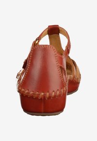 Sandali in pelle rossa con tallone chiuso, punta aperta e tagli laterali. Cuciture decorative lungo i bordi per un tocco di dettaglio in più.