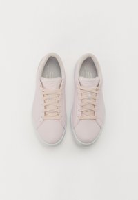 Light pink athletic shoes with a smooth fabric upper, round toe, and thin laces. Features a white rubber sole and grey padded inner lining.