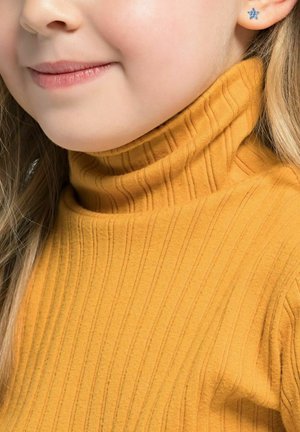 Maglione giallo a coste con colletto aderente. Piccolo orecchino blu a forma di stella visibile vicino all'orecchio. Tessuto morbido e strutturato.