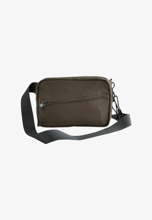 Kompakte olivgrüne Umhängetasche mit vorne diagonal verlaufender Reißverschlusstasche und verstellbarem, breitem grauem Riemen.