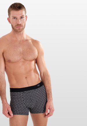 Schwarz-weiße bedruckte Boxershorts mit einem weichen Bund. Sie haben ein geometrisches Design und eine figurbetonte Form, hergestellt aus dehnbarem Stoff.