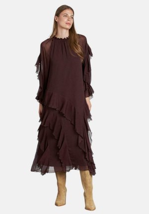 Vestido de capas en color burdeos con acentos con volantes, mangas transparentes y un escote redondo. Combinado con botas de caña alta texturizadas en color beige.